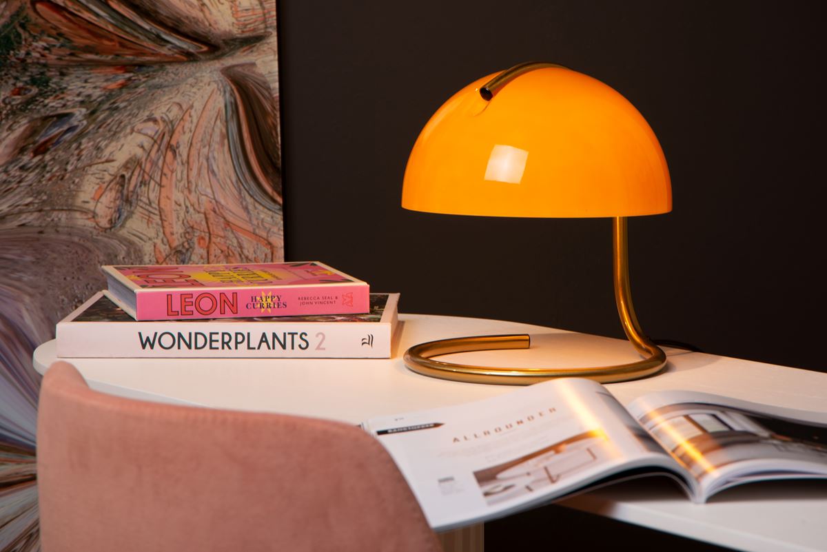 Lampe Lucide Cato orange allumée sur un bureau avec des livres