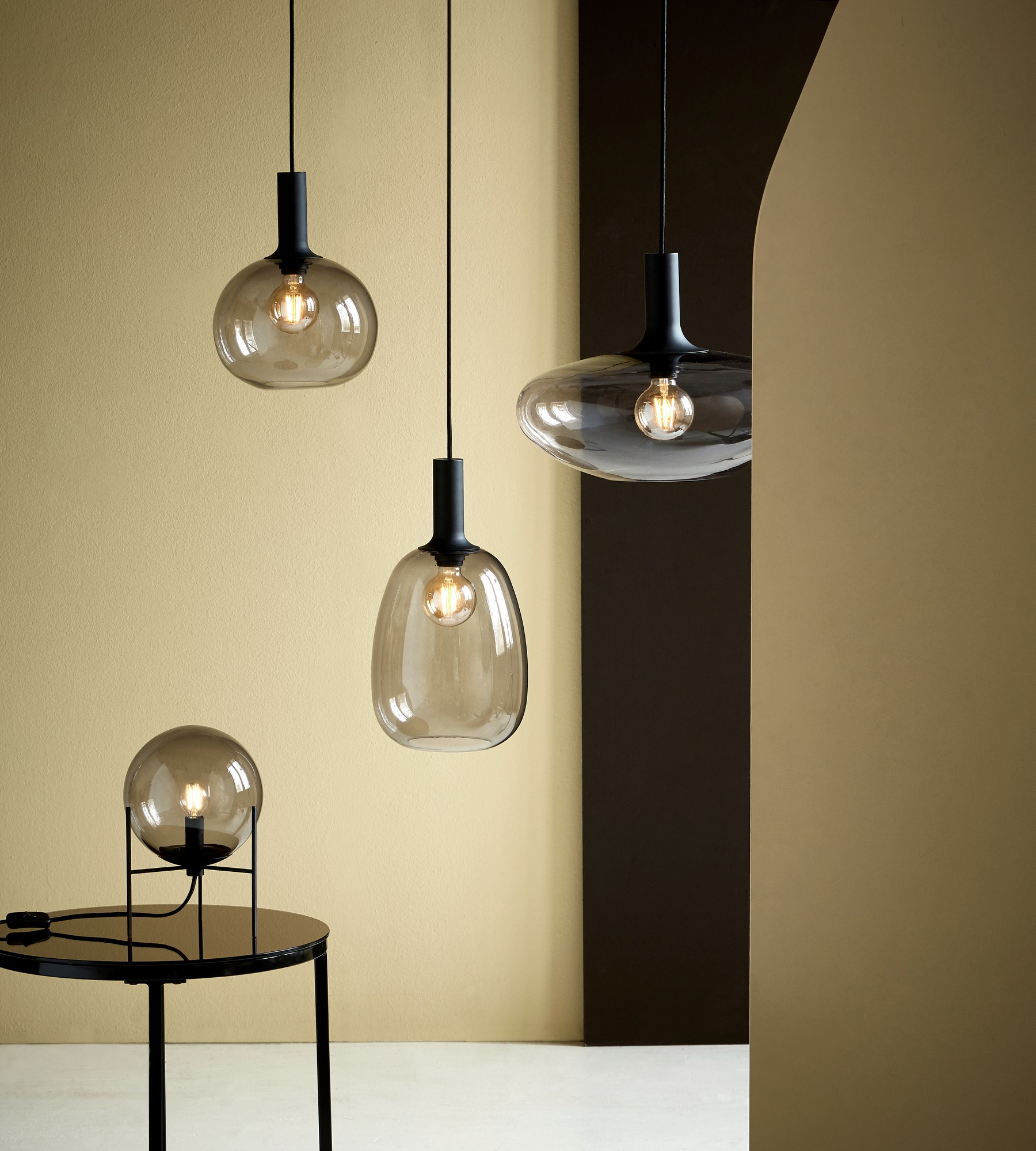 Suspensions Nordlux Alton en verre soufflé fumé au-dessus d’une table