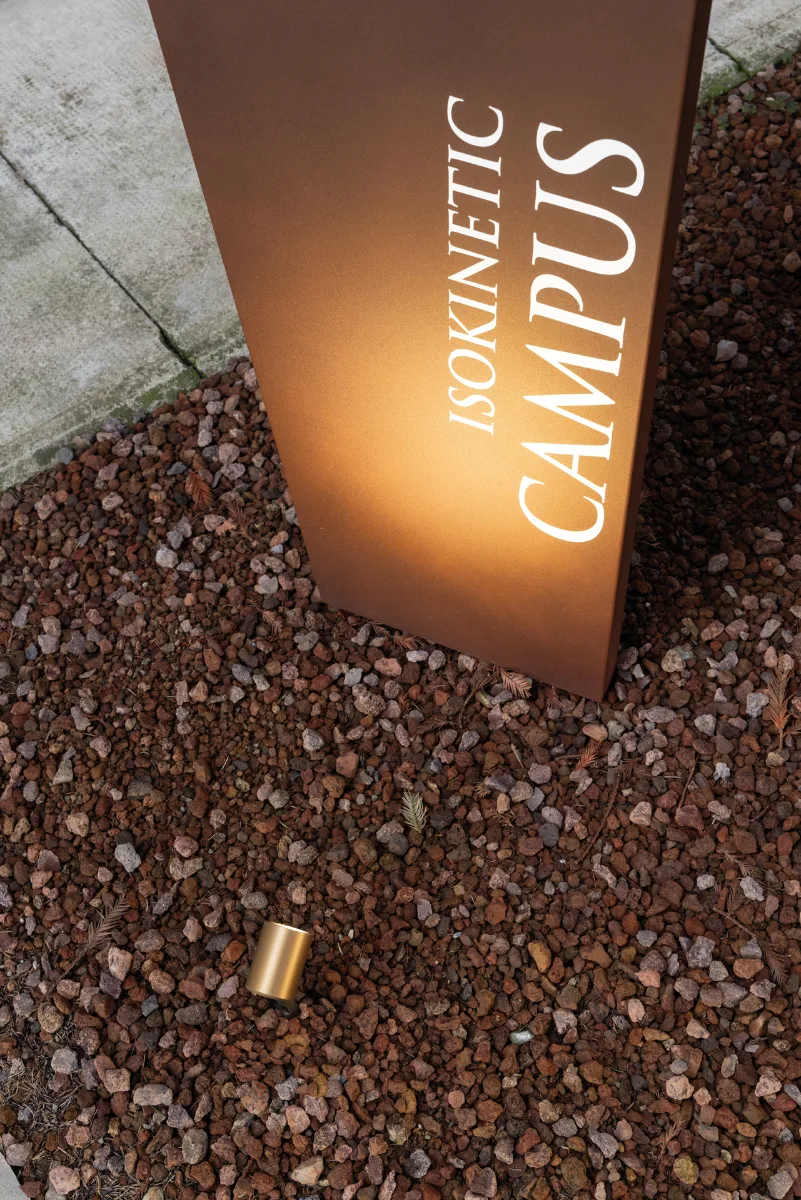 Petit projecteur Lombardo Ago en finition laiton éclairant un totem en acier corten