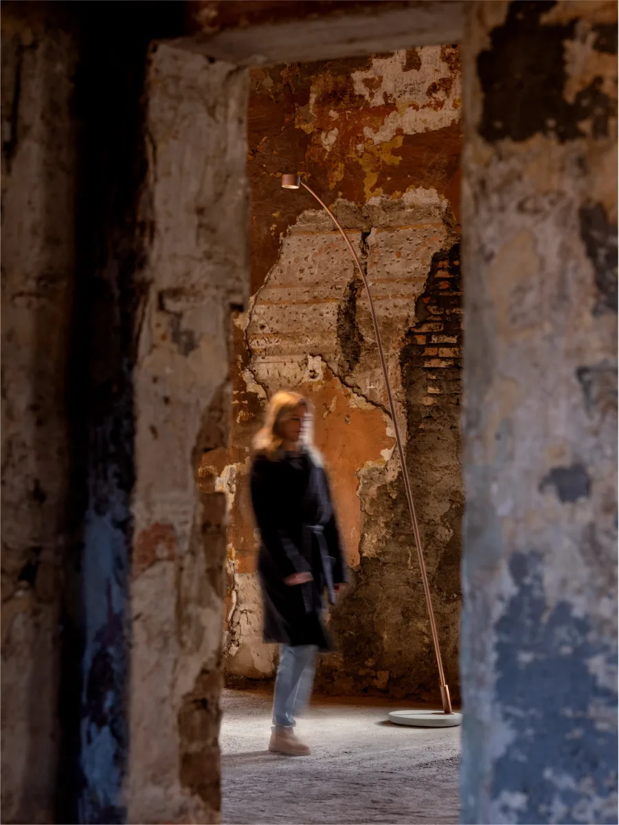 Lampadaire Lombardo Hasta R éclairant un passage dans un bâtiment ancien aux murs de pierre